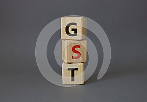 GST - Goods and Services Tax symbol. Concept word GST on wooden cubes. Beautiful grey background. Business and GST concept. Copy