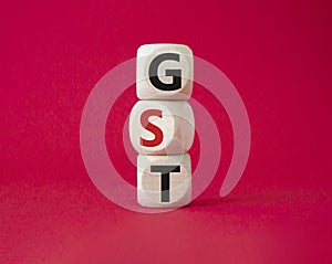 GST - Goods and Services Tax symbol. Concept word GST on wooden cubes. Beautiful red background. Business and GST concept. Copy