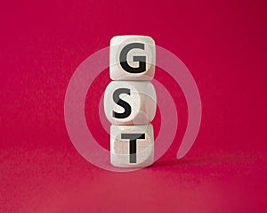 GST - Goods and Services Tax symbol. Concept word GST on wooden cubes. Beautiful red background. Business and GST concept. Copy