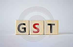GST - Goods and Services Tax symbol. Concept word GST on wooden cubes. Beautiful white background. Business and GST concept. Copy