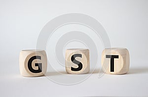 GST - Goods and Services Tax symbol. Concept word GST on wooden cubes. Beautiful white background. Business and GST concept. Copy