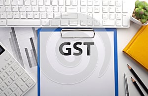 GST written on paper with keyboard, chart, calculator and notebook