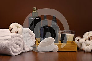 Gua sha facial stone, cosmetic bottles, towels and candle on wooden background still life stock photo images