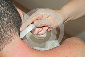 Gua sha massage. The masseuse`s hands closeup. A man gets a massage.