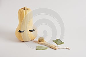 Gua Sha Scrapers, wooden massage brush and pumpkin with false eyelashes gray background, face massage