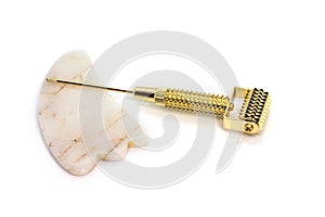 Gua sha stone and golden mesoscooter isolated on white background. marble gua sha stone for face sculpting. non-invasive facial photo