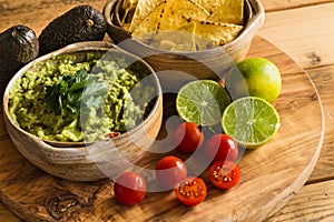 Guacamole dip in bowl with tortilla chips and ingredients