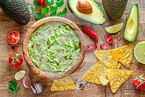 Guacamole, guacamole ingredients and chips on wooden background. Flat lay