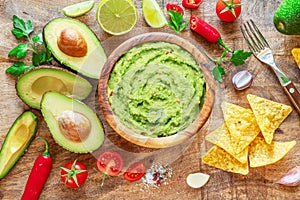 Guacamole, guacamole ingredients and chips on wooden background. Flat lay