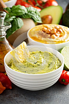 Guacamole and hummus in white bowls