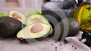 guacamole ingredients - Avocados whole and cut on concrete table with a marble mortar