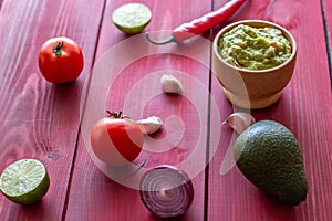 Guacamole and ingredients. Red background. Mexican cuisine