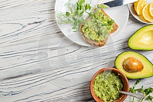 Guacamole ingredients on wooden table, avocado, lemon, spices and whole grain bread toast