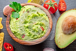 Guacamole sauce and guacamole ingredients, popular Mexican food, on slate serving board. Top view