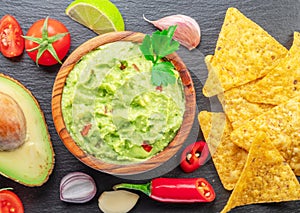 Guacamole sauce and guacamole ingredients, popular Mexican food, on slate serving board. Top view