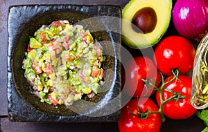 Guacamole in stone mortar and ingredients. Top view