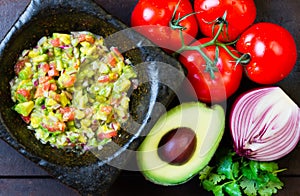 Guacamole in stone mortar and ingredients. Top view