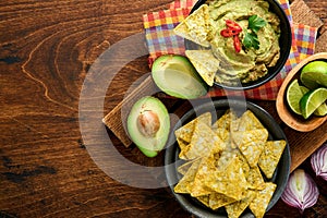 Guacamole. Traditional latinamerican Mexican dip sauce in a black bowl with avocado and ingredients and corn nachos. Avocado
