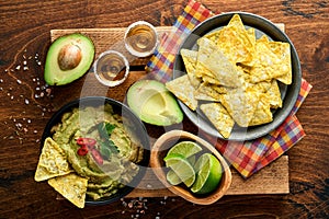 Guacamole. Traditional latinamerican Mexican dip sauce in a black bowl with avocado and ingredients and corn nachos. Avocado