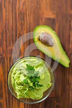 Guacamole on wooden table surrounded by its ingridients