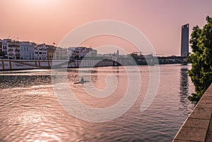 Guadalquivir river with silhouette of a canoeist, and architecture of city at evening, SPAIN
