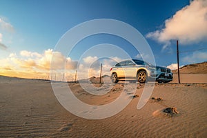 Road through sand dunes at sunset and BMW car. Guadalupe-Nipomo Dunes National Wildlife Reserve, California