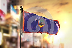 Guam Flag Against City Blurred Background At Sunrise Backlight