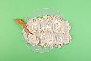 Guar gum powder or guarana in wooden spoon, top view. Inscription GUAR GUM. Design element. Food additive E412. Fat Replacer,