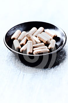 Guarana capsules. Bright wooden background. Close up.