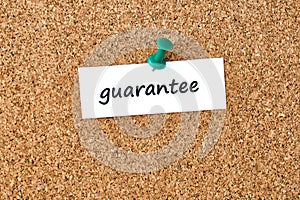 Guarantee. Word written on a piece of paper, cork board background