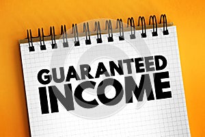 Guaranteed Income - social-welfare system that guarantees all citizens or families an income sufficient to live on, text concept photo