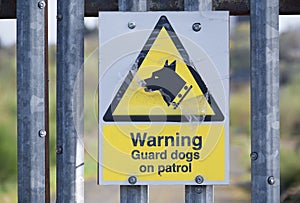 Guard dogs on patrol warning sign on security fence at construction site