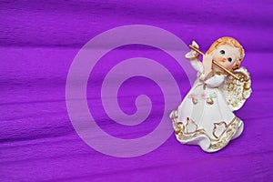Guardian angel plays the flute. Figurine of a red-haired girl in a white dress with wings and a pipe. New Year or