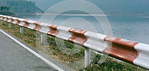 Guardrail traffic barrier painted red and white block road line on crest reservoir dam