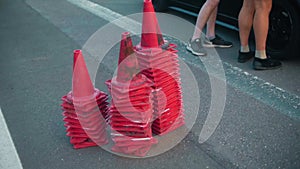 Guards cones are stacked in separate piles on the track next to the sports car