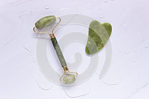 A guasha scraper and a green jade stone roller. Self-care, anti-aging facial massage, spa