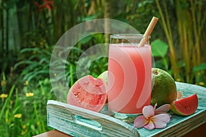 Guava smoothie in glass with bamboo drinking straw