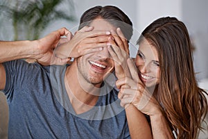 Guess what I got you. a young woman covering her husbands eyes for a surprise.