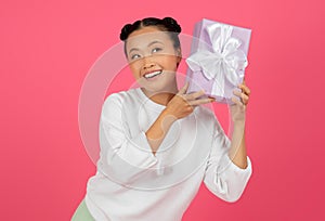 Guess what's inside. Surprised asian woman listening what rattles in gift box