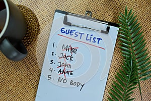 Guest List write on a paperwork and supported by additional services isolated on Wooden Table