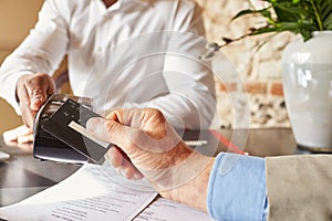 Guest making contactless card payment at hotel, hands detail