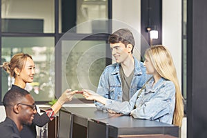 Guests handing their check-in information to the hotel receptionist with a smile