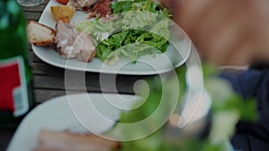 Guests serve green tasty salad on picnic table