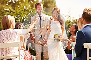 Guests Throwing Confetti Over Bride And Groom At Wedding photo