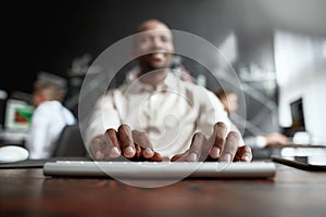 Guide a better future. Focused african male trader sitting by desk and studying analytical reports using pc in the