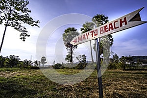 Guide post `way to beach`on old rice fieldand palm tree