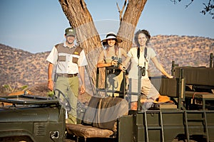 Guide and two brunettes in jeep smiling