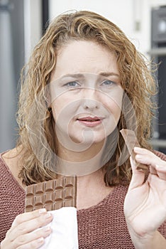 Guilty Woman On Diet Eating Chocolate Bar At Home