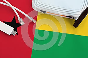 Guinea Bissau flag depicted on table with internet rj45 cable, wireless usb wifi adapter and router. Internet connection concept