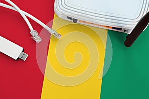 Guinea flag depicted on table with internet rj45 cable, wireless usb wifi adapter and router. Internet connection concept